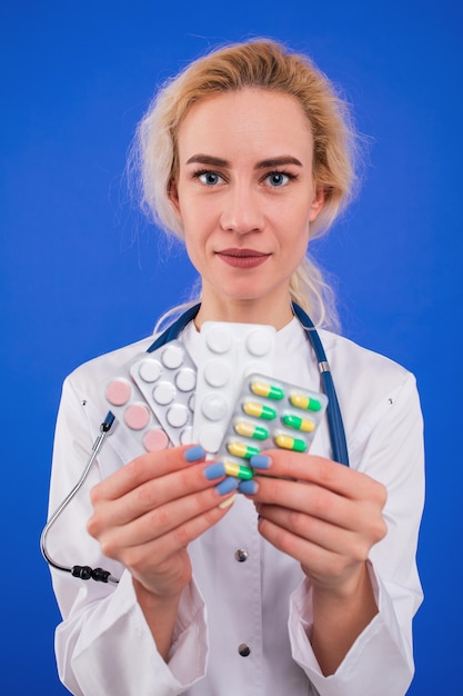 A nurse holds pills on a blue background