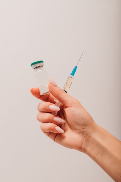 A nurse holds a syringe and a vaccine in her hands
