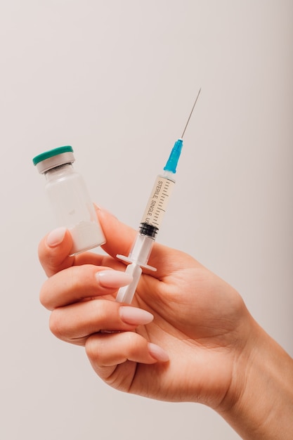 A nurse holds a syringe and a vaccine in her hands