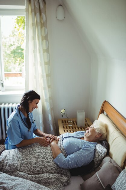 Nurse interacting with senior woman on bed