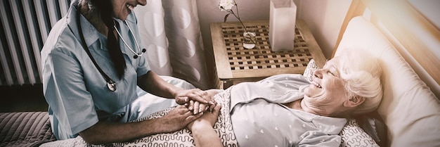 Photo nurse interacting with senior woman on bed