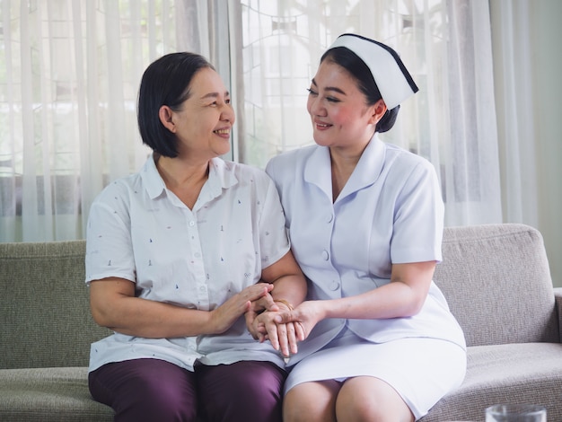 The nurse is caring for the elderly with happiness, Caregiver placed his hand on the hand of senior woman