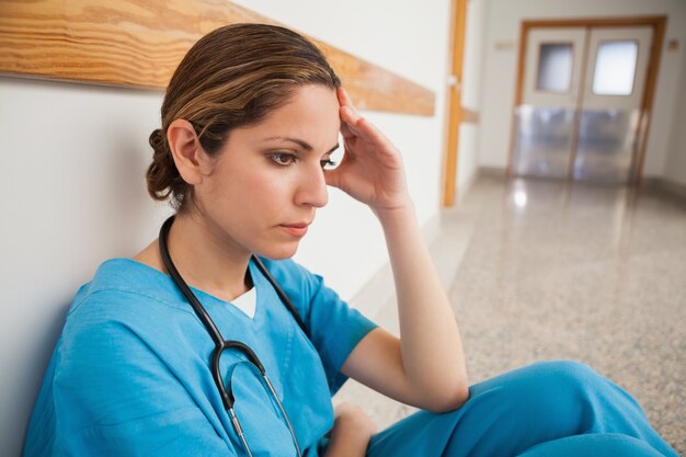 Photo nurse is sitting on the floor thinking