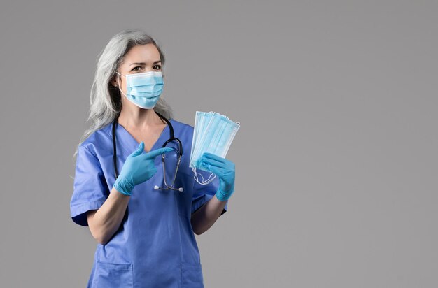 Nurse lady posing with medical face masks on gray background