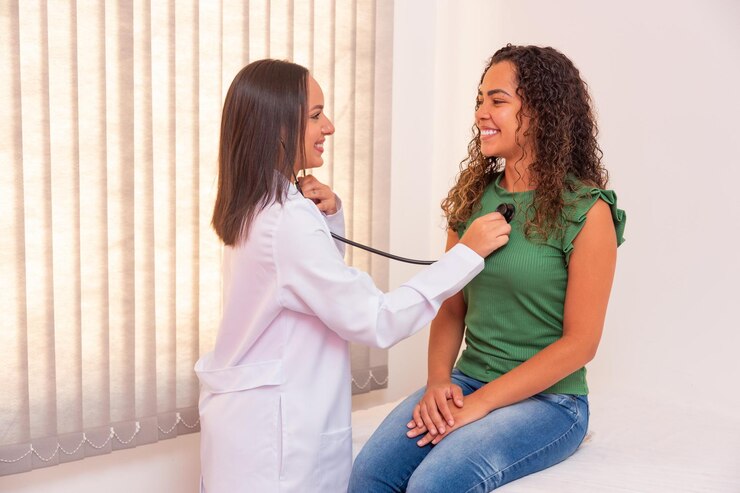 Nurse listening to the heart of an afro female patient in consultation. Examining the patient