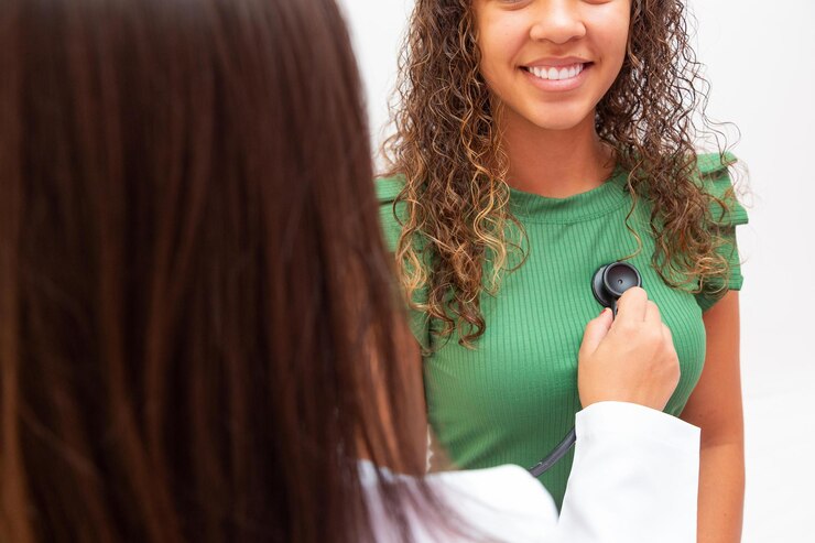 Nurse listening to the heart of an afro female patient in consultation. Examining the patient