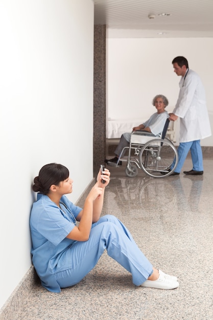 Photo nurse looking at her mobile phone