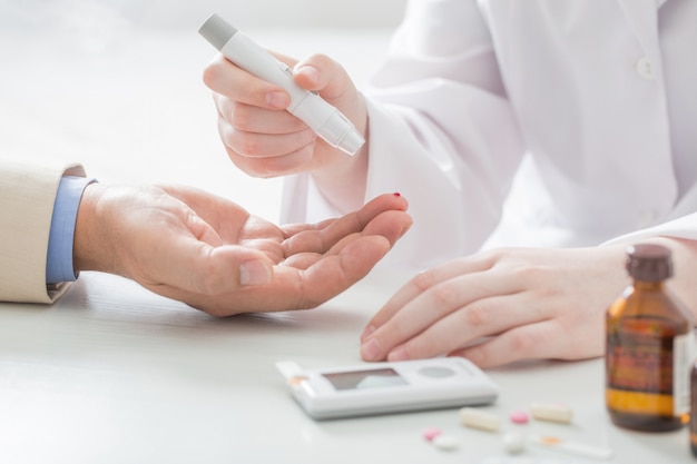 Nurse measures the level of sugar in the blood of  businessman