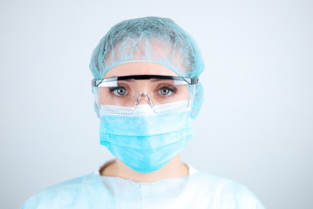 Медсестра в медицинском халате, маске и защитных перчатках с прозрачными очками