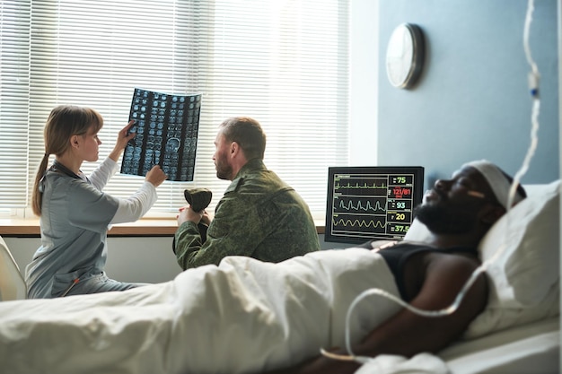 Nurse in medical scrubs explaining xray results to soldier in military uniform