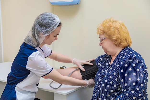 A nurse in a polyclinic measures the blood pressure of a woman with a device Healthcare