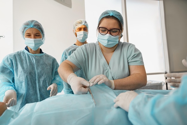 Nurse prepares a patient for surgery against the background of medical colleagues