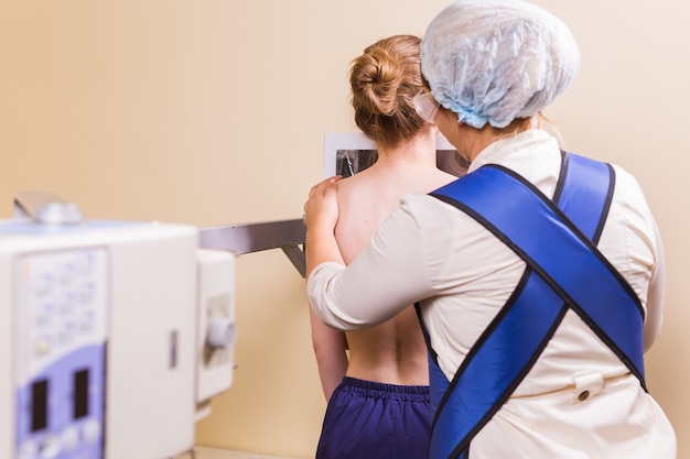 Photo nurse preparing patient for chest xray in examination room