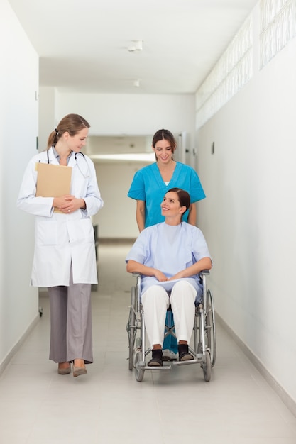 Nurse pushing a patient in a wheelchair while talking to a doctor