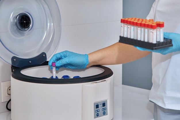 A nurse puts test tubes in a centrifuge