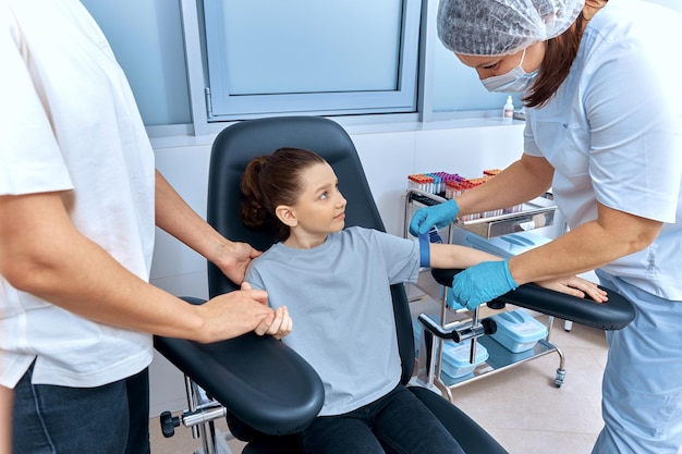 Photo the nurse puts a tourniquet on the girl's arm