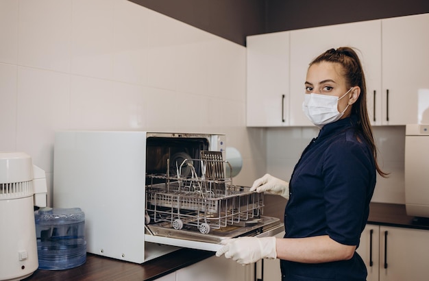 Photo nurse putting instruments in special craft paper bags into autoclave for processinglaboratory equipment tools sterilization bacterial purification and disinfection in dental clinic selective focus