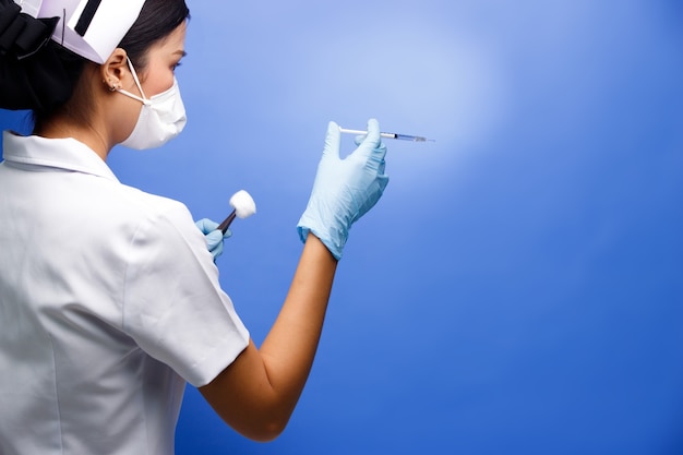 Nurse ready to inject vaccine in Syringe into empty patient. Nurse act to make a Shot with side view. Blue background isolated. Health and medical concepts