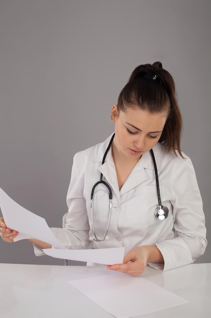 Nurse in  robe and with stethoscope on her neck is making her report at the table