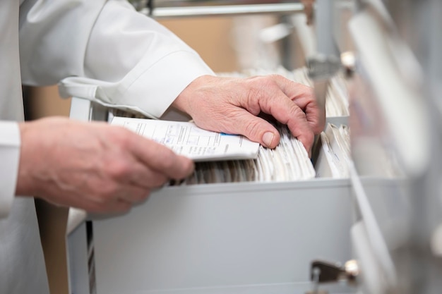 The nurse's hands are looking in the archive for a patient's card