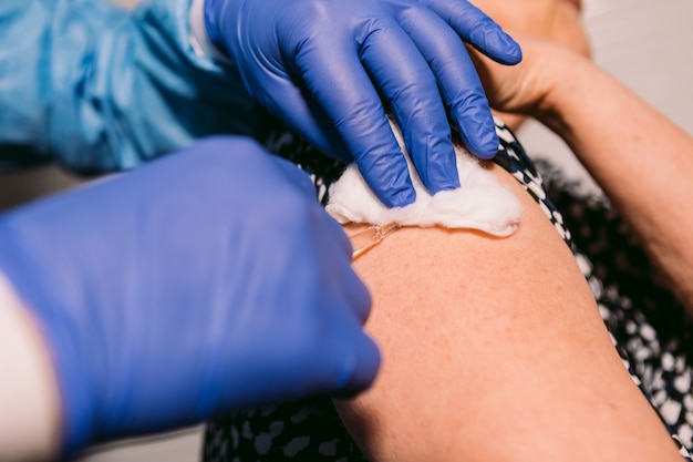 Nurse's hands inject a vaccine into an older woman's arm