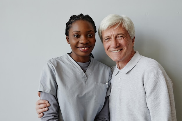 Nurse and senior man smiling at camera together