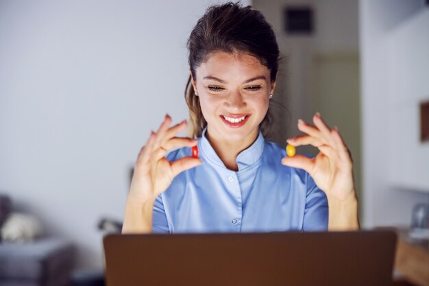 Nurse sitting at home and holding pills in her hands. She is giving advices over internet.