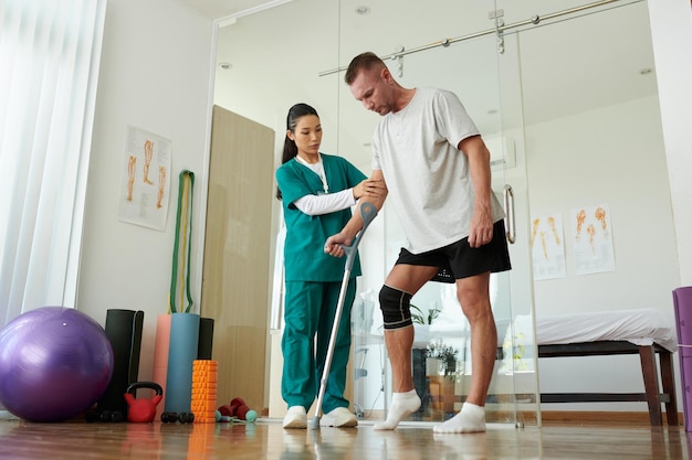 Photo nurse supporting patient learning to walk