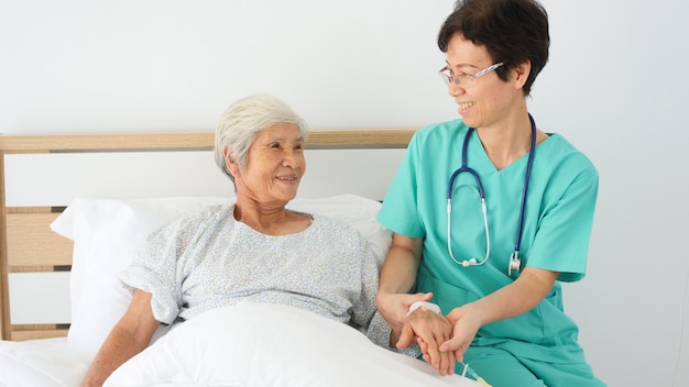 Nurse take care elderly woman in hospital room.