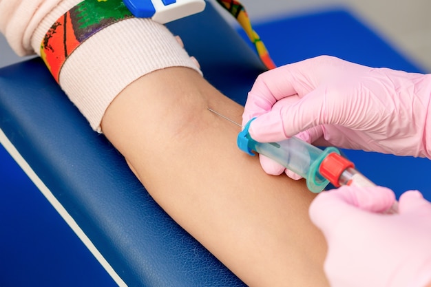 看護師は、女性の腕の静脈に針を導入して採血を行います。