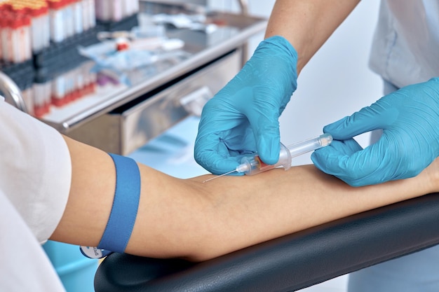 A nurse takes a woman's blood from a vein for analysis closeup