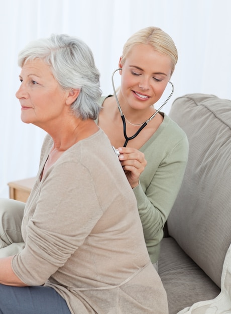 Nurse taking the heartbreat of her patient at home