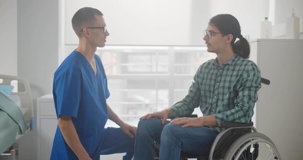 Медсестра принимает молодого человека в инвалидной коляске в больничной палате