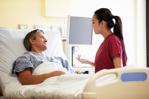 nurse talking to male patient in hospital room
