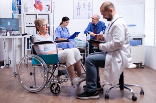 Infermiera che parla con un uomo disabile nella stanza d'ospedale durante la consultazione