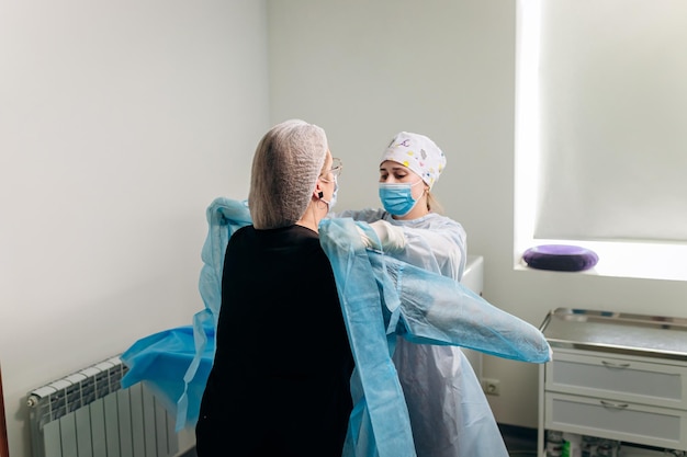 Nurse ties a sterile gown to the surgeon before the operation Doctors prepare for surgery in the operating room put on a medical uniform