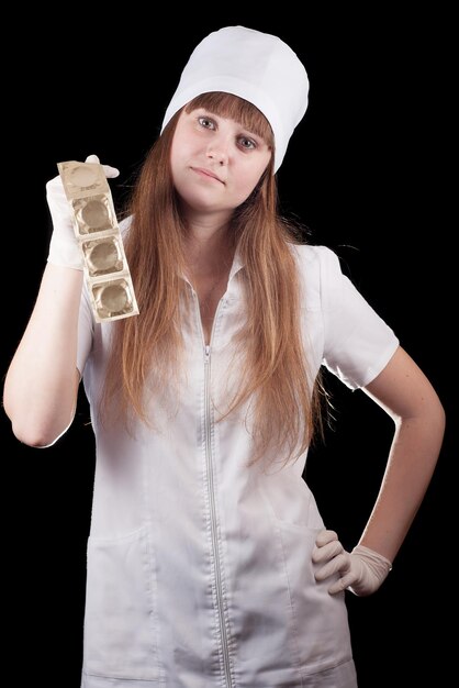 Медсестра в униформе держит презервативы на черном фоне