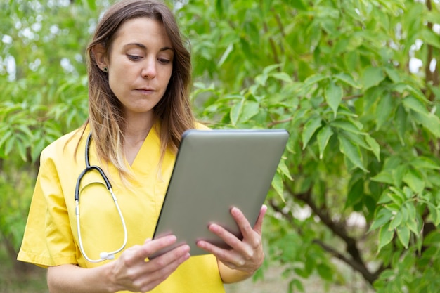 Nurse in uniform looking intently at the tablet she holds in her hands