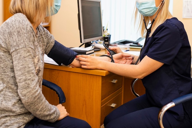 A nurse in uniform measures the pressure of a patient