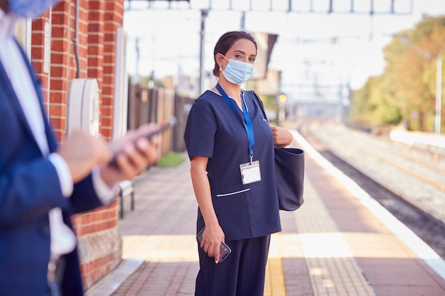 Nurse In Uniform On Railway Platform Wearing Ppe Face Mask Commuting To Work During Pandemic