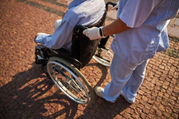 Infermiera in uniforme che si prende cura del paziente disabile in sedia a rotelle