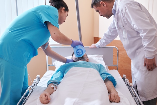 백 밸브 마스크를 사용하는 간호사는 의사의 통제하에 위독한 상태의 환자에게 환기를 제공합니다.
