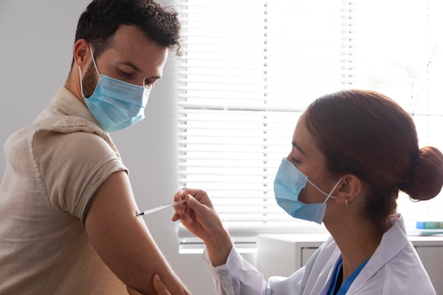 Foto infermiera che vaccina un paziente maschio