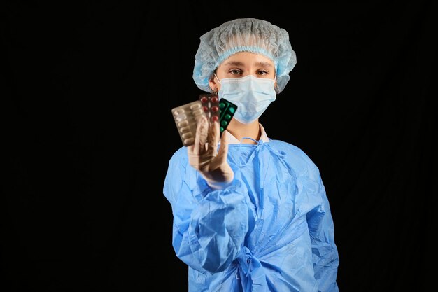 A nurse virologist in a mask holds pills in his hands Coronavirus vaccine  Quarantine