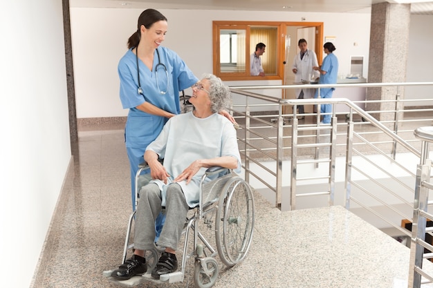 車椅子に座っている古い女性を見守っている看護婦
