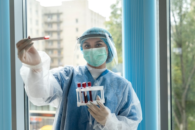 Nurse wearing face shield uniform holding positive blood test result for COVID-19. Concept of Covid-19 quarantine.