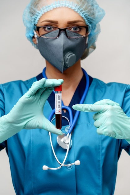 Nurse wearing protective mask and gloves and holding positive coronavirus COVID-19 blood test