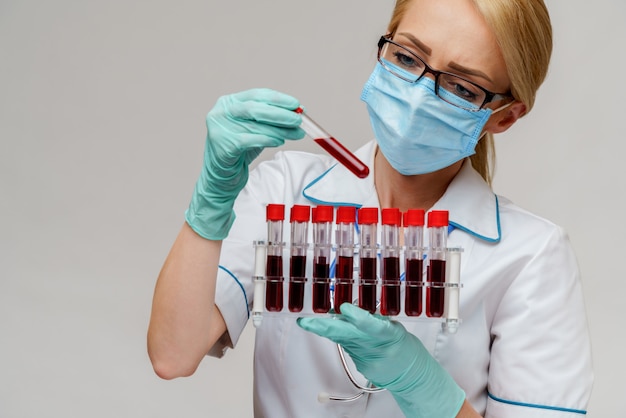 Nurse wearing protective mask and gloves and holding rack with virus blood tests