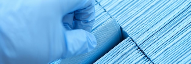 Nurse wearing protective rubber gloves pulling out sterile blue medical napkin closeup