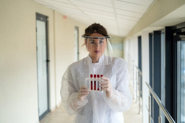 Nurse wearing scrubs holding and looking at blood test tube in lab